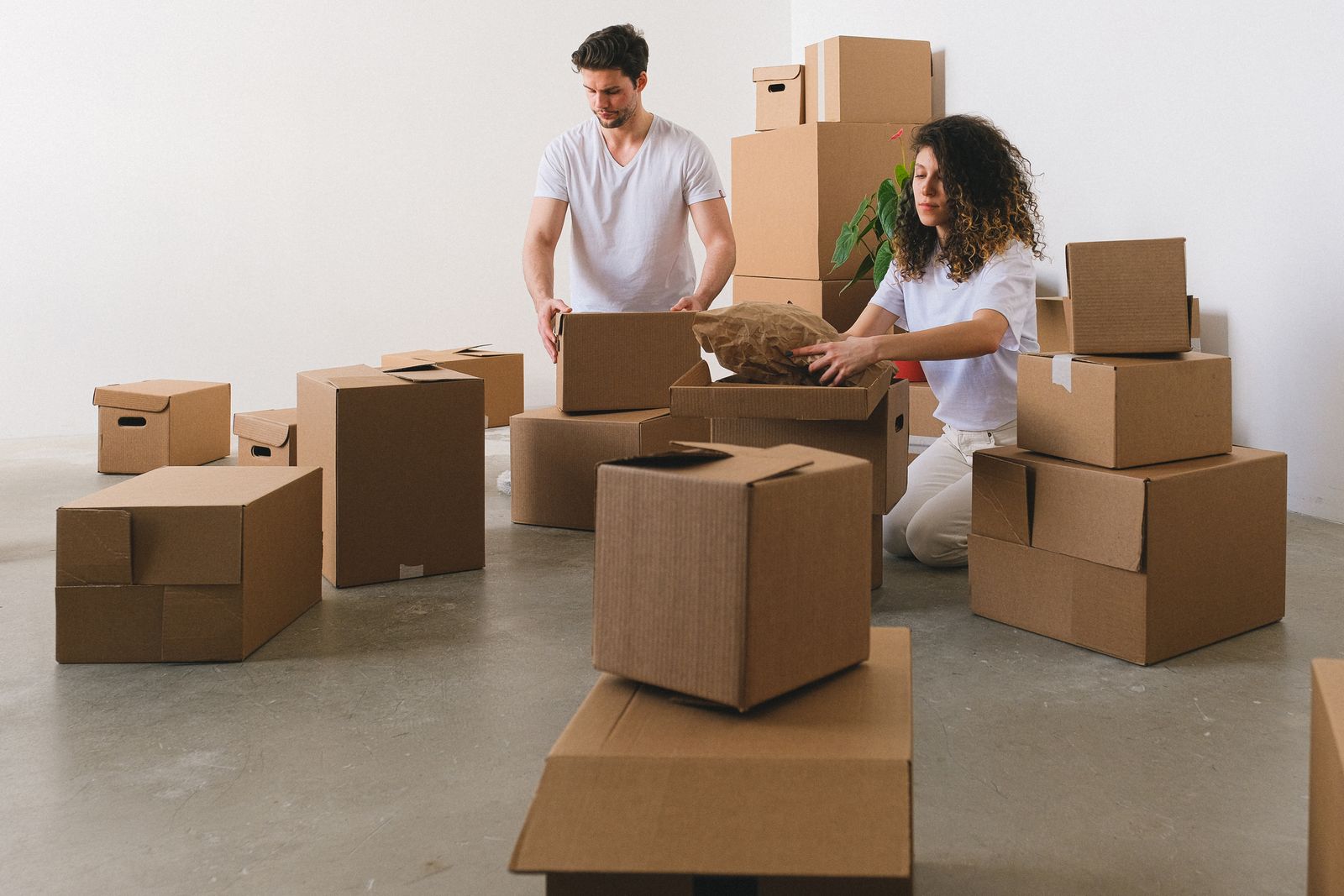 Couple packing their belongings into cardboard boxes at home.